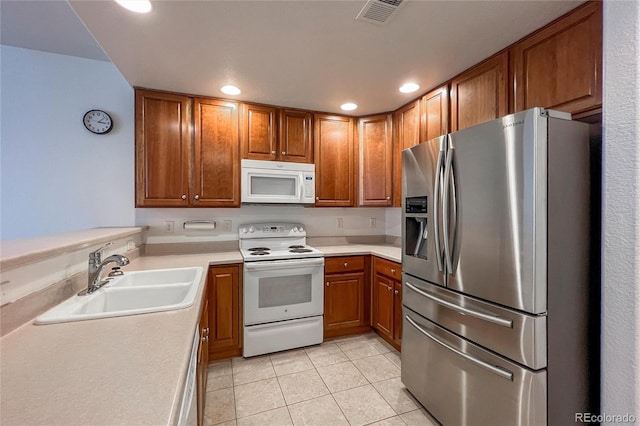 kitchen featuring white appliances, sink, and light tile patterned floors