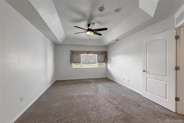 empty room with ceiling fan, a raised ceiling, carpet floors, and a textured ceiling