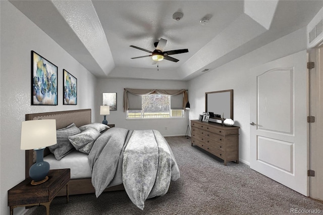 bedroom featuring a textured ceiling, a raised ceiling, ceiling fan, and carpet flooring