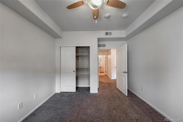 unfurnished bedroom featuring ceiling fan, dark carpet, and a closet