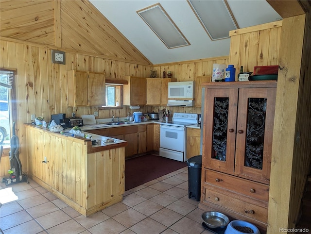 kitchen featuring lofted ceiling, white appliances, wooden walls, light tile patterned floors, and kitchen peninsula