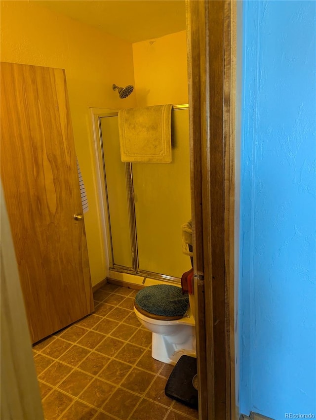 bathroom with tile patterned floors, a shower with door, and toilet