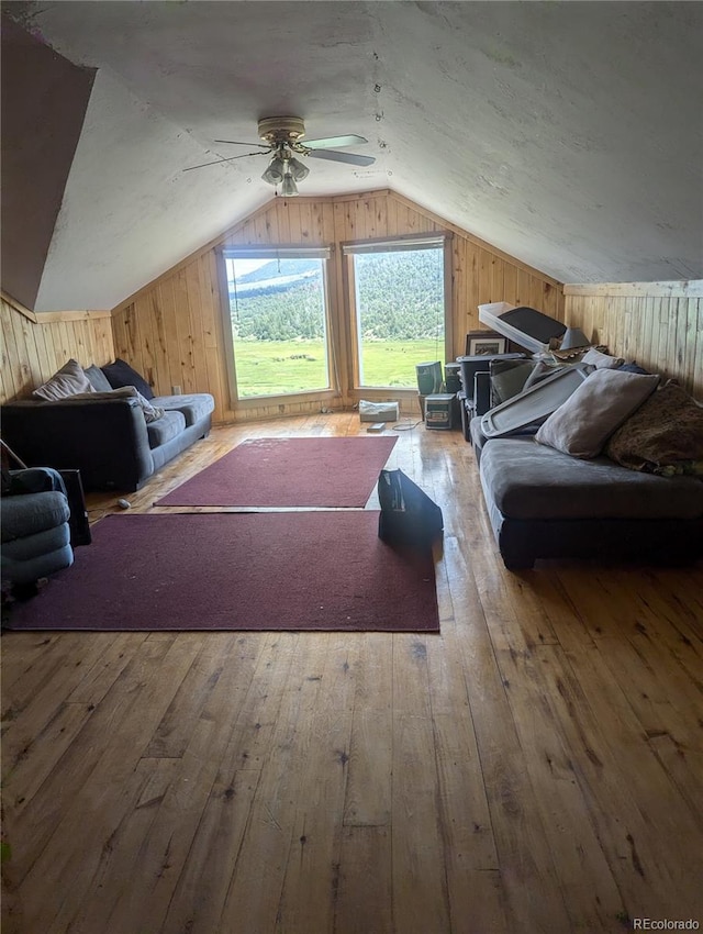 bonus room with ceiling fan, wooden walls, wood-type flooring, and lofted ceiling