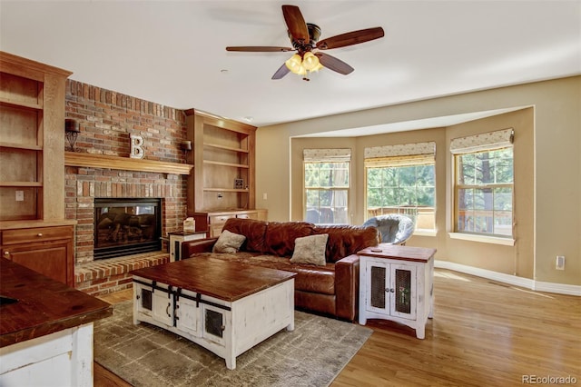 living room featuring a brick fireplace, wood-type flooring, and ceiling fan