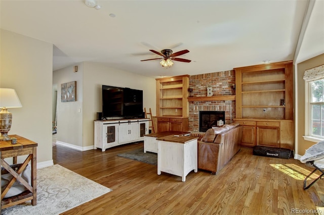 living room with a brick fireplace, ceiling fan, and light wood-type flooring