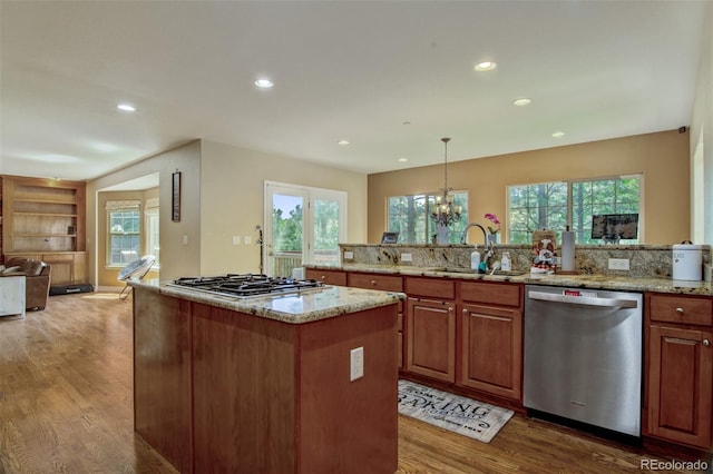 kitchen featuring hanging light fixtures, appliances with stainless steel finishes, a center island, and light stone counters