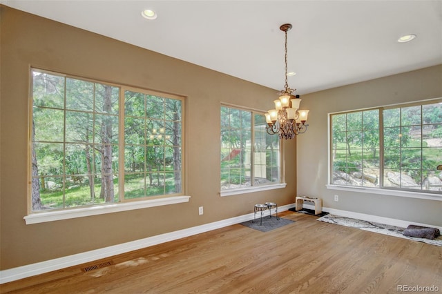 unfurnished dining area with an inviting chandelier and hardwood / wood-style floors