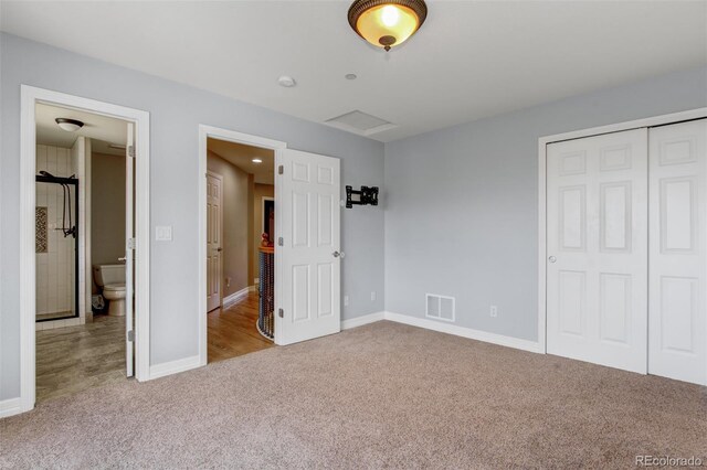 unfurnished bedroom with light colored carpet, ensuite bath, and a closet