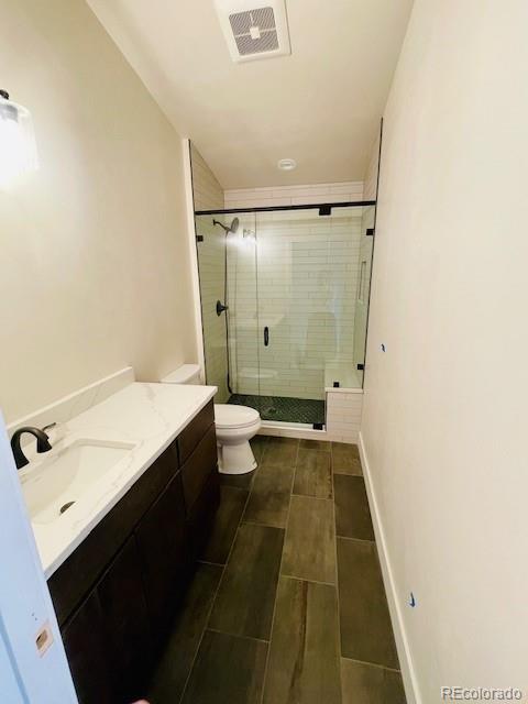 full bath with a stall shower, visible vents, vanity, and toilet