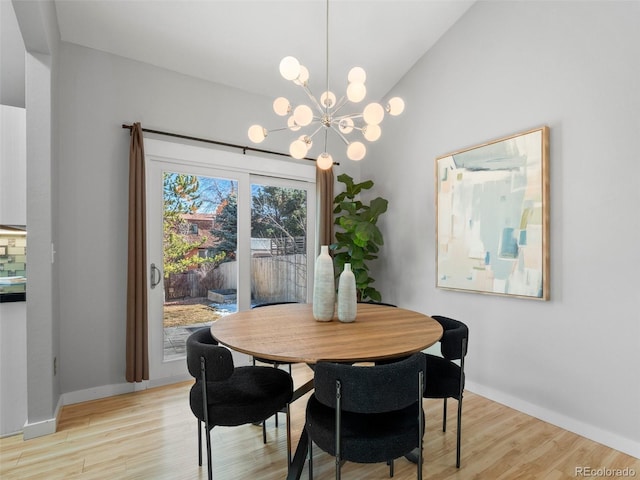 dining room with light wood-style floors, lofted ceiling, a notable chandelier, and baseboards