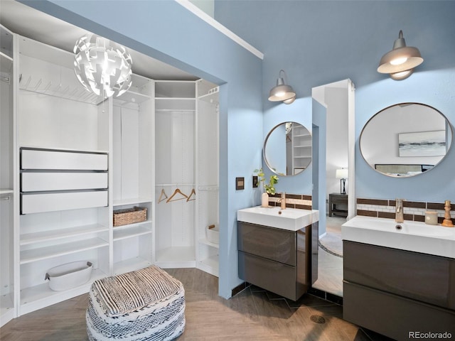 bathroom featuring a shower, two vanities, and a sink