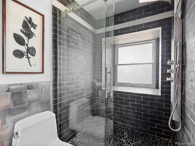 bathroom featuring a stall shower, toilet, and tile walls