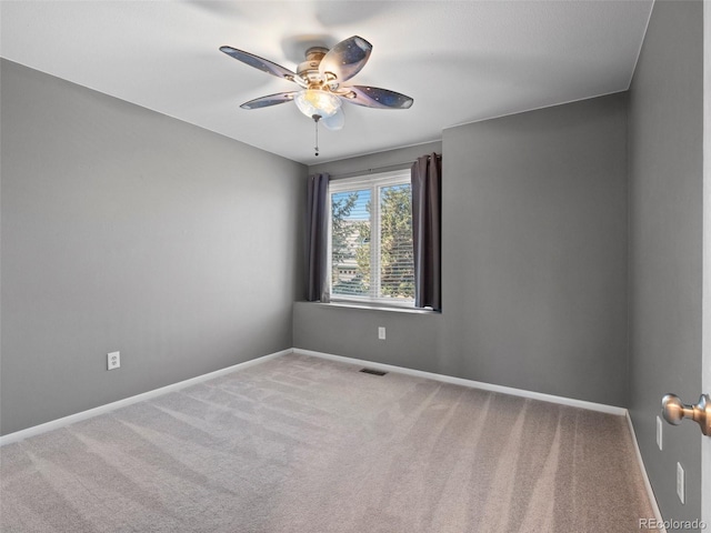 empty room featuring ceiling fan, carpet floors, visible vents, and baseboards