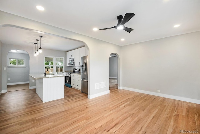 5100 Clay St, Denver, CO 80221 - kitchen with stainless steel appliances, arched walkways, a sink, white cabinetry, and baseboards