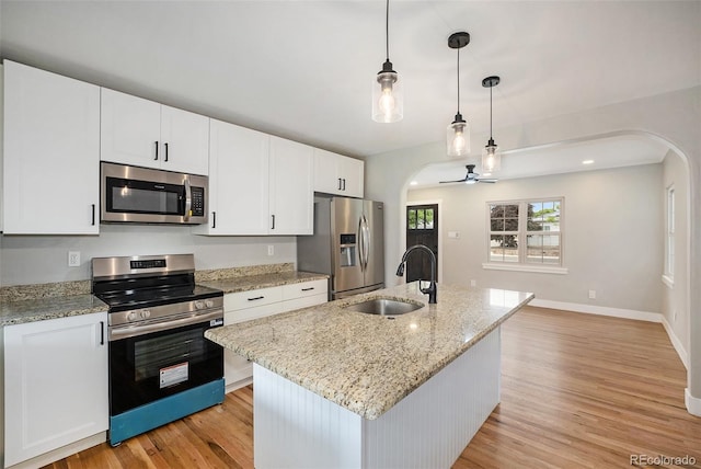 5100 Clay St, Denver, CO 80221 - kitchen with stainless steel appliances, arched walkways, a sink, and light wood-style flooring