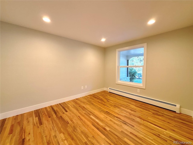 unfurnished room featuring light wood-type flooring and a baseboard radiator