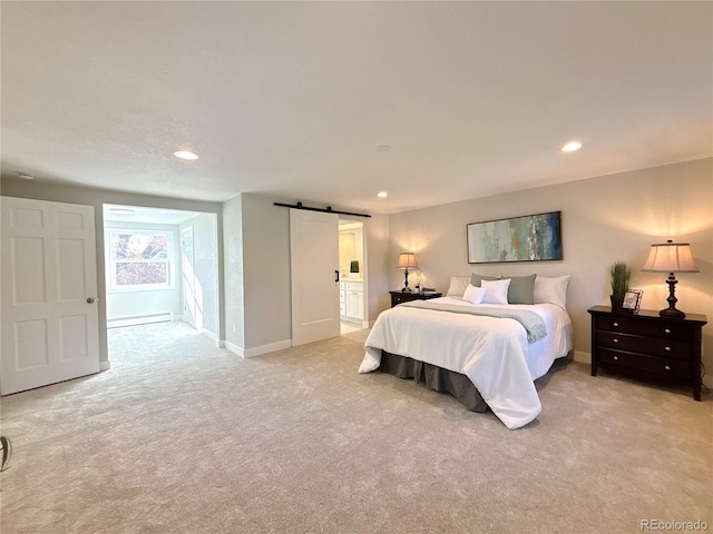 bedroom featuring baseboard heating, a barn door, ensuite bathroom, and light colored carpet