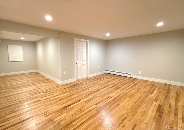 spare room with light wood-type flooring and a baseboard heating unit