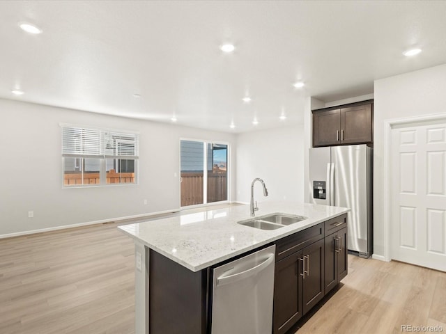 kitchen with sink, a kitchen island with sink, dark brown cabinets, appliances with stainless steel finishes, and light wood-type flooring