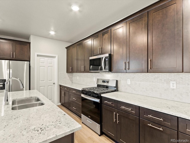 kitchen with light stone countertops, appliances with stainless steel finishes, backsplash, and sink