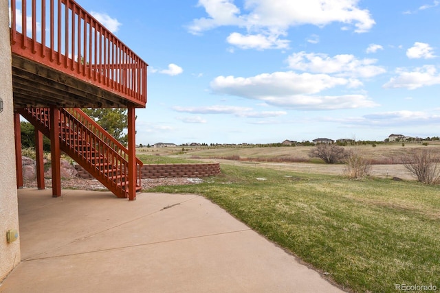 view of yard with a rural view, a patio, and a wooden deck