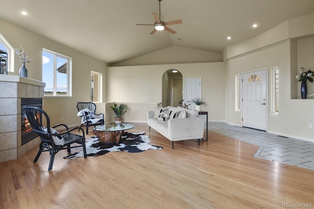 living room featuring a fireplace, vaulted ceiling, and light hardwood / wood-style flooring