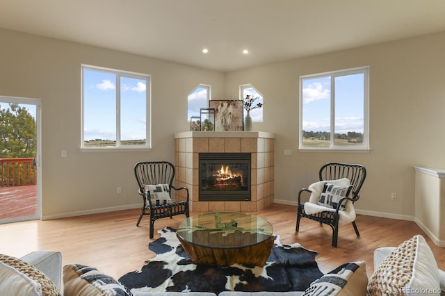 sitting room featuring a tile fireplace, a healthy amount of sunlight, and light wood-type flooring