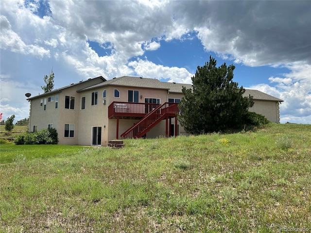 back of property with a wooden deck and a yard