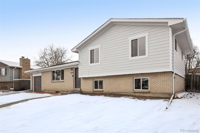 snow covered house featuring a garage