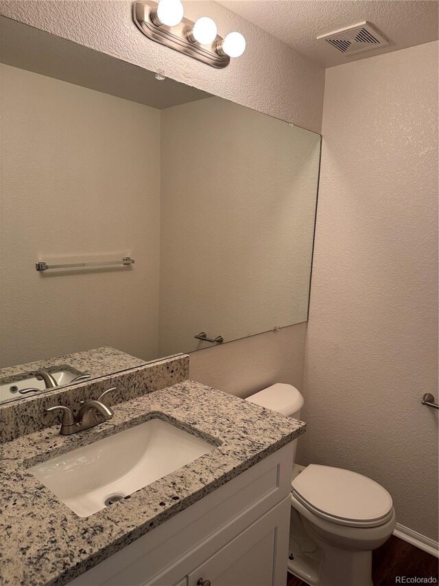 13959 Eudora St, Thornton, CO 80602 - bathroom featuring vanity, toilet, wood finished floors, and a textured ceiling