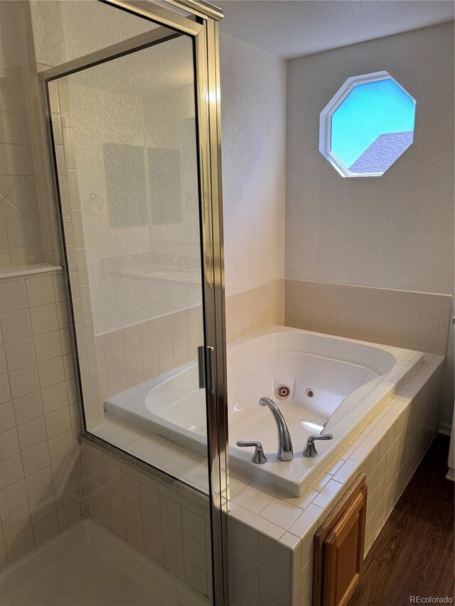 13959 Eudora St, Thornton, CO 80602 - full bathroom featuring wood finished floors, a tub with jets, a stall shower, and a textured wall