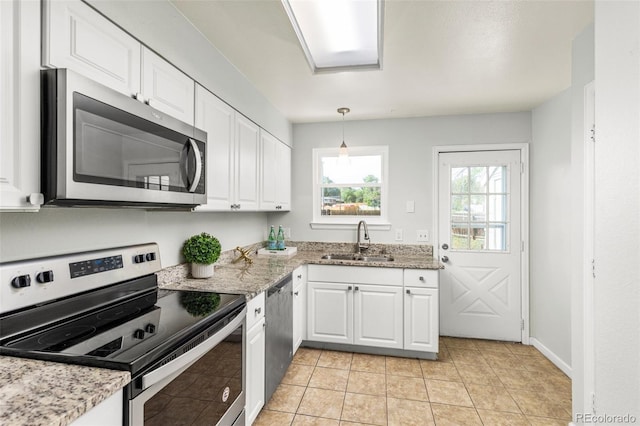 8260 Washington St Unit 78, Denver, CO 80229 - kitchen with stainless steel appliances, white cabinets, hanging light fixtures, light stone counters, and light tile patterned floors
