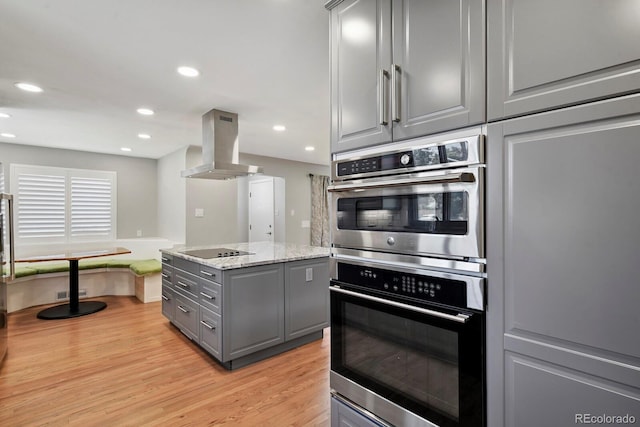 10595 E 23rd Ave, Aurora, CO 80010 - kitchen featuring gray cabinetry, island exhaust hood, stainless steel double oven, black electric stovetop, and light wood-style flooring