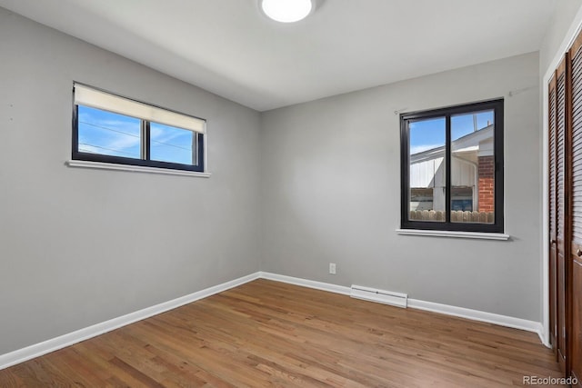 10595 E 23rd Ave, Aurora, CO 80010 - spare room with healthy amount of natural light, wood finished floors, and a baseboard radiator
