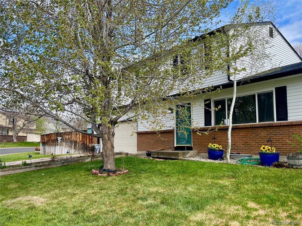 exterior space featuring a garage, a front lawn, and brick siding