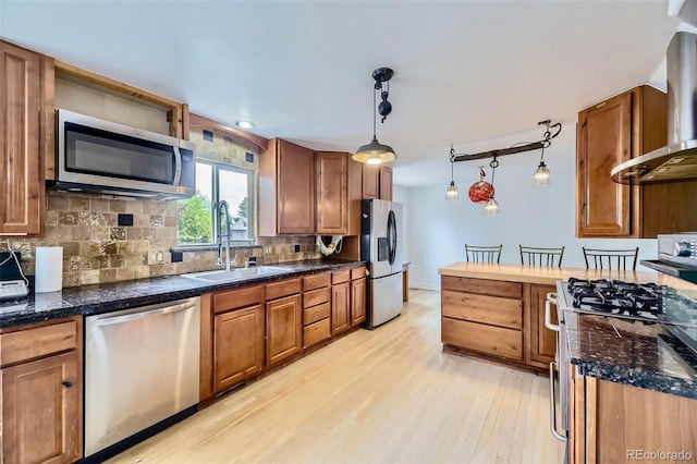 4934 S Flower Way, Littleton, CO 80123 - kitchen with stainless steel appliances, a sink, wall chimney exhaust hood, tile counters, and light wood-style flooring