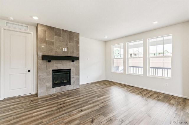 unfurnished living room featuring a tiled fireplace and hardwood / wood-style floors