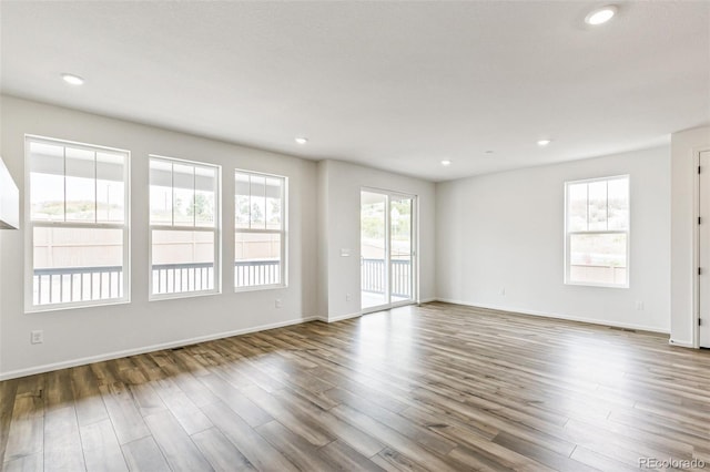 empty room with hardwood / wood-style flooring and a wealth of natural light