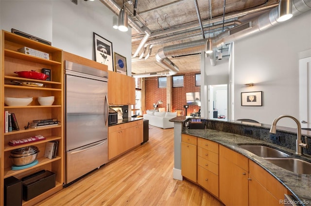 kitchen featuring light wood finished floors, open shelves, visible vents, a sink, and built in refrigerator