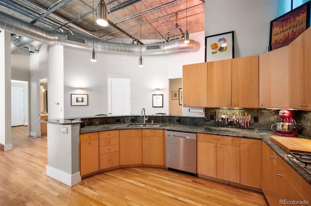 kitchen featuring a high ceiling, dishwasher, a peninsula, and a sink