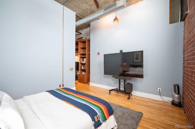 bedroom with wood finished floors, visible vents, and baseboards