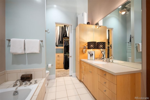 bathroom featuring toilet, tile patterned floors, a spacious closet, vanity, and a bath