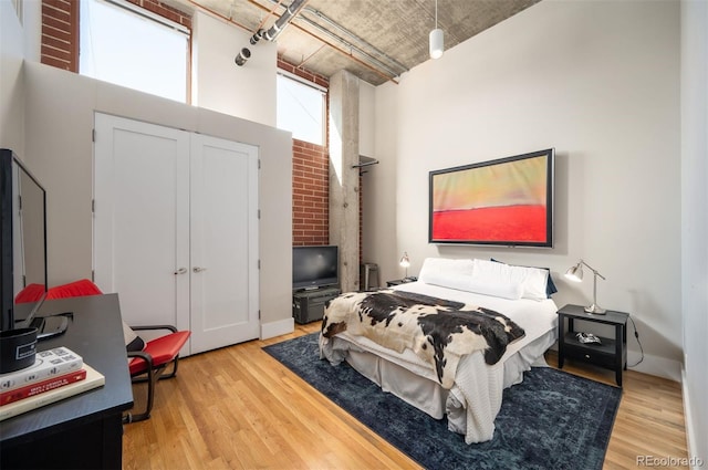 bedroom with light wood finished floors, a closet, and a towering ceiling