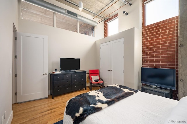 bedroom featuring a towering ceiling and wood finished floors