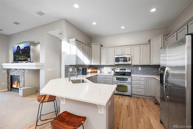 kitchen featuring stainless steel appliances, a peninsula, and gray cabinetry