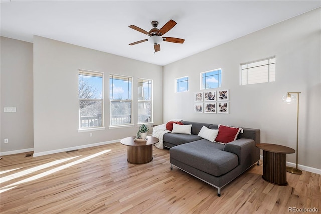 living room with ceiling fan, light wood-style flooring, and baseboards