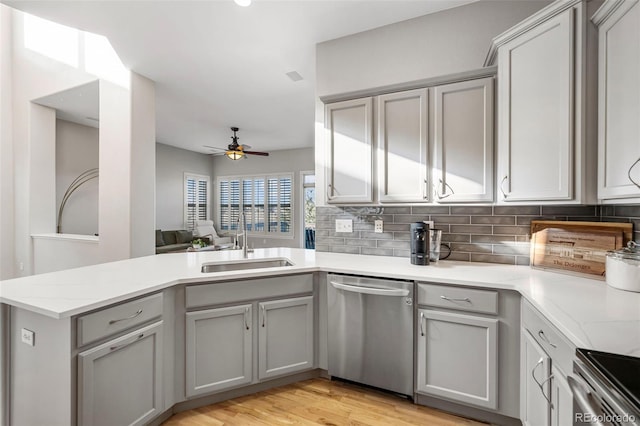 kitchen featuring backsplash, stainless steel dishwasher, a sink, ceiling fan, and a peninsula