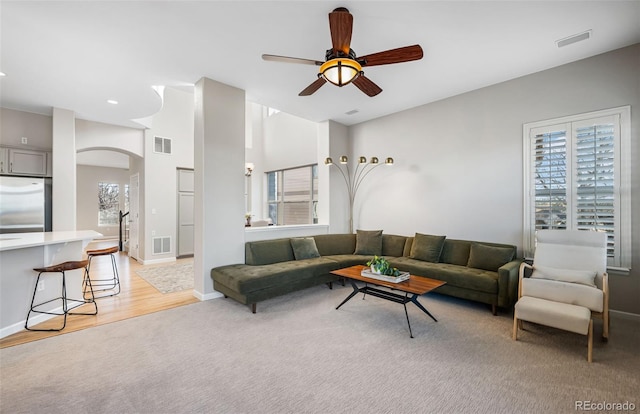 living room with a ceiling fan, arched walkways, and visible vents