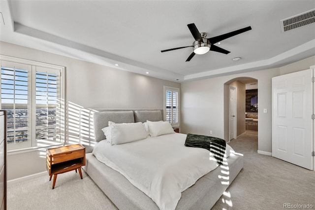 bedroom with arched walkways, baseboards, visible vents, and a tray ceiling