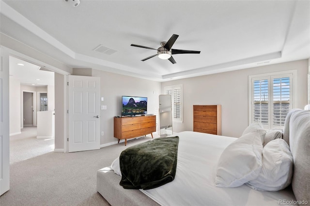 bedroom featuring a raised ceiling, light carpet, visible vents, and baseboards